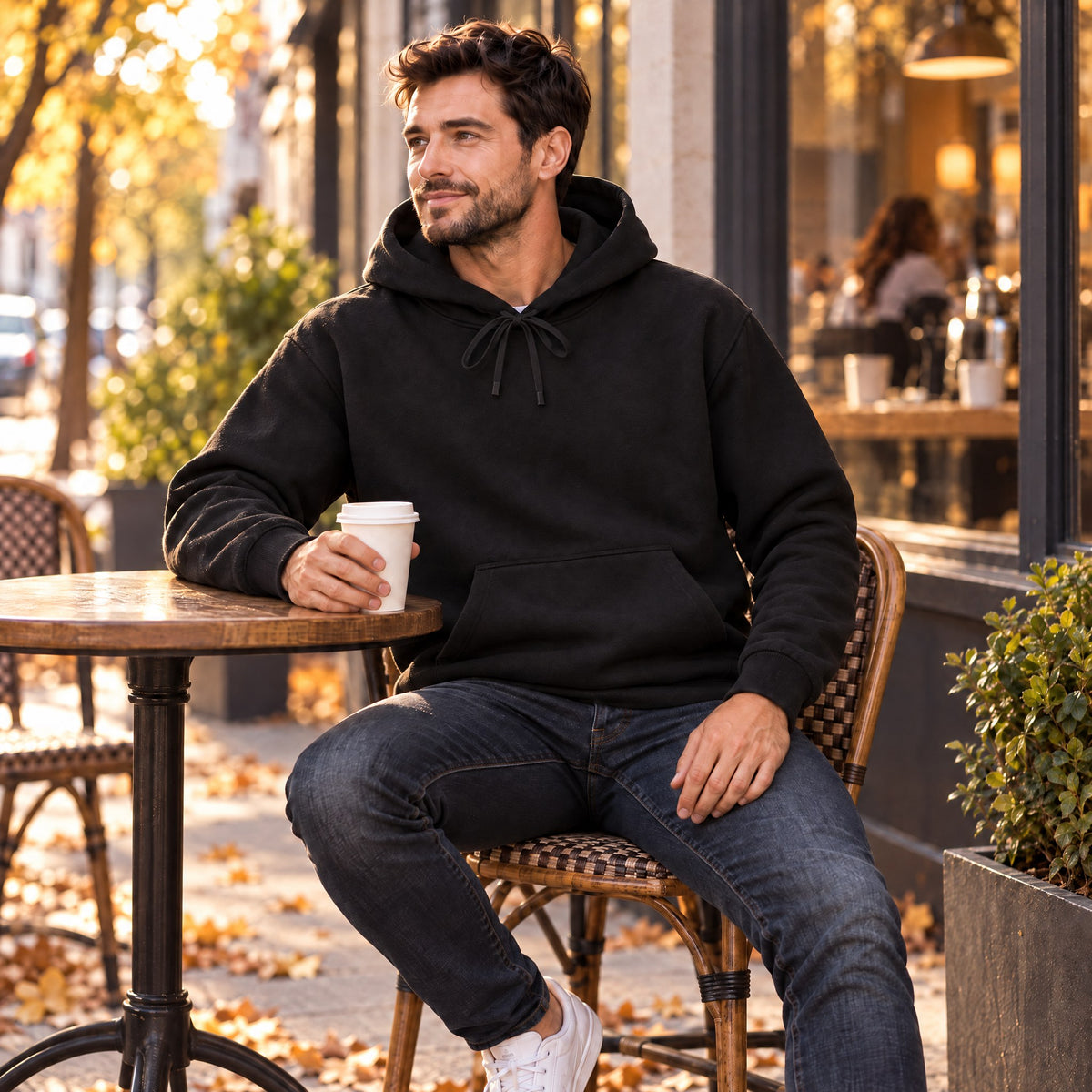 Alessio Classic Pullover Hoodie for Men in black, worn at an outdoor cafe table